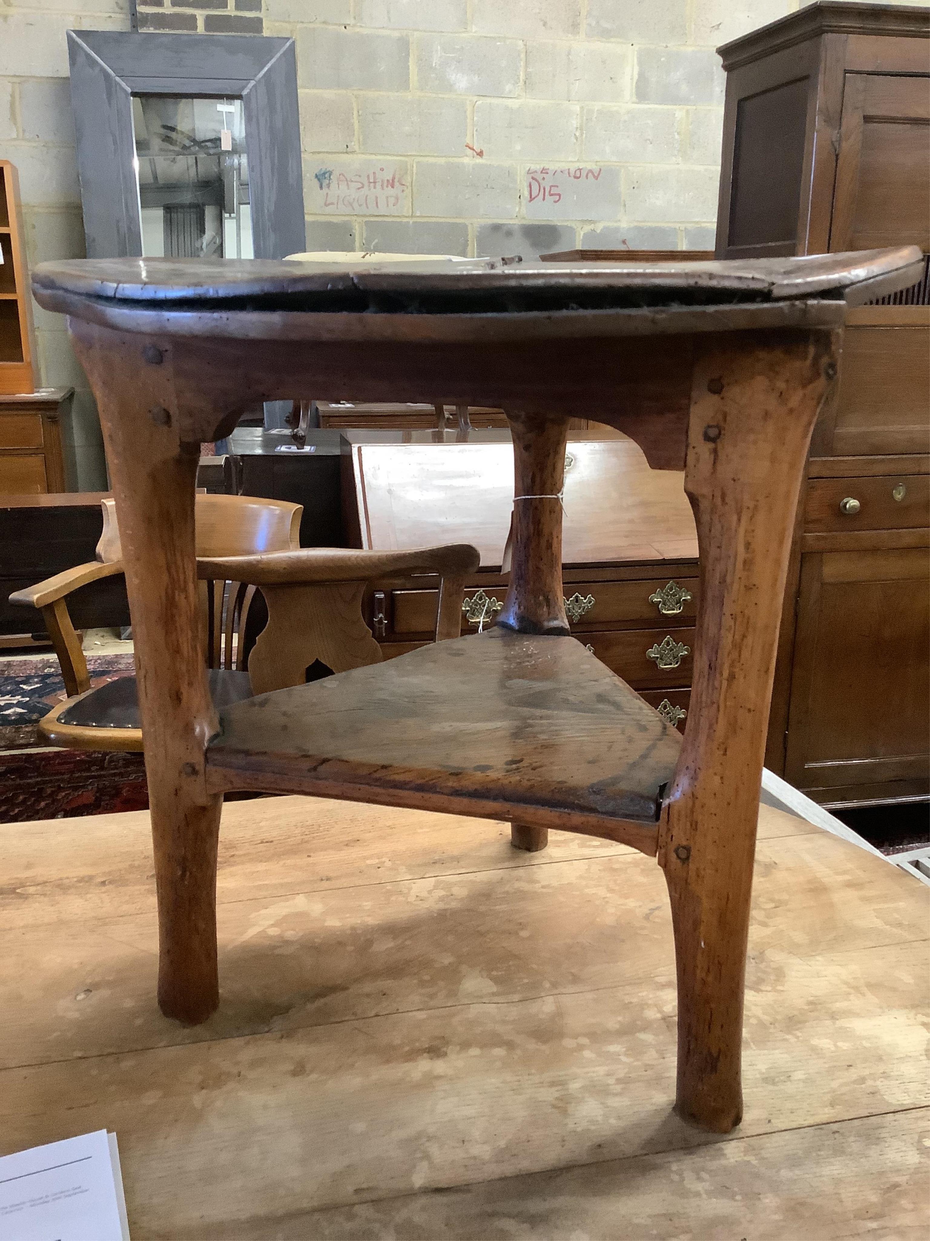 An 18th century elm cricket table, width 63cm, height 64cm. Condition - extensive splitting and old patches and repairs to the top, legs probably reduced, but full of character
